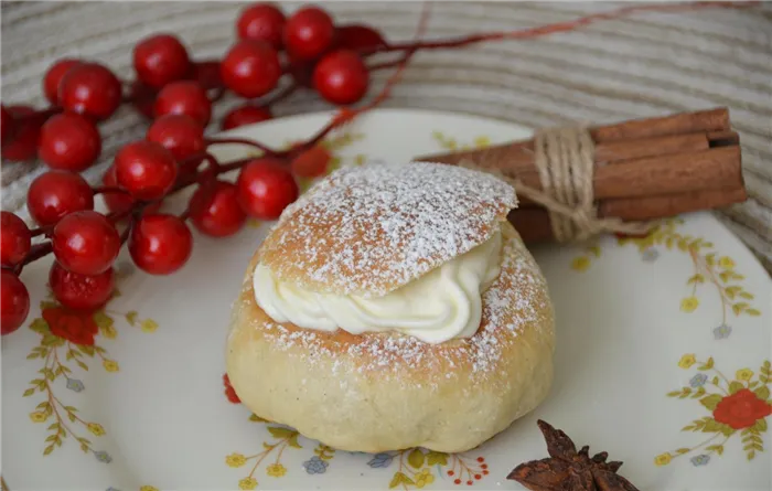 булочка с марципановой массой и кардамоном, украшенная сахарной пудрой, на тарелке